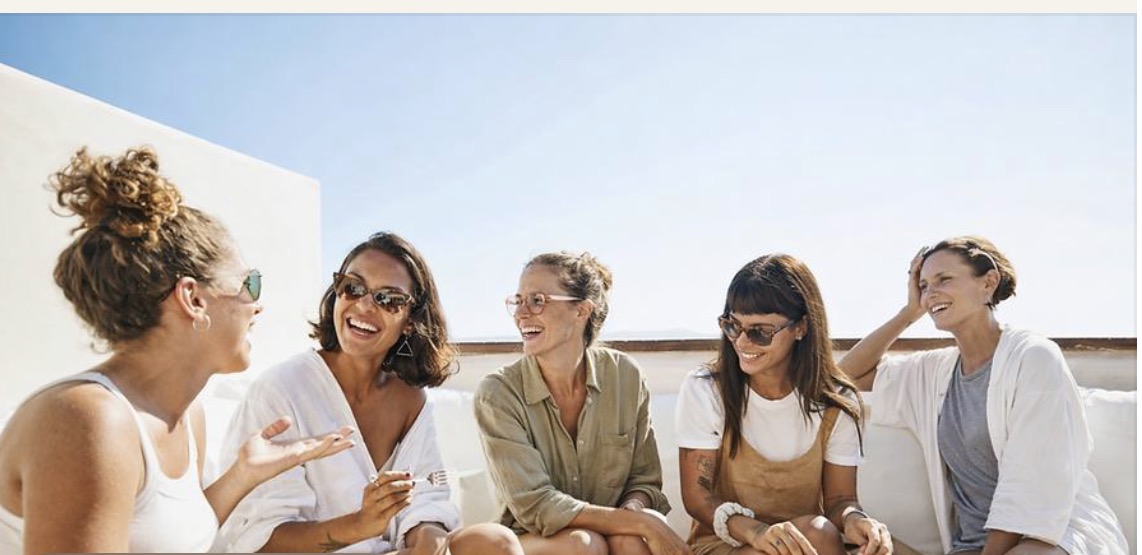 A group of mothers laughing and catching up together in the sunshine